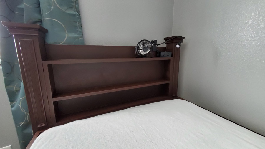 Shelves on bed with lamp, fan and outlet