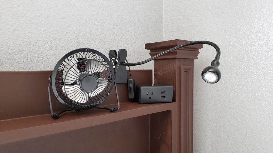 Shelves on bed with lamp, fan and outlet